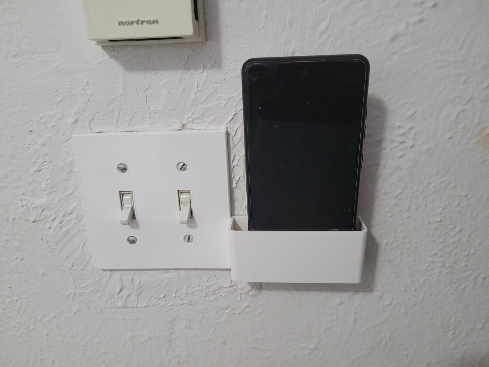 Double switch plate phone holder installed on a dual light switch