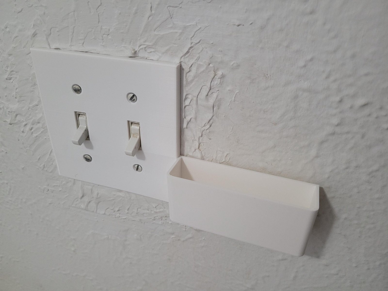Double switch plate phone holder holding a phone