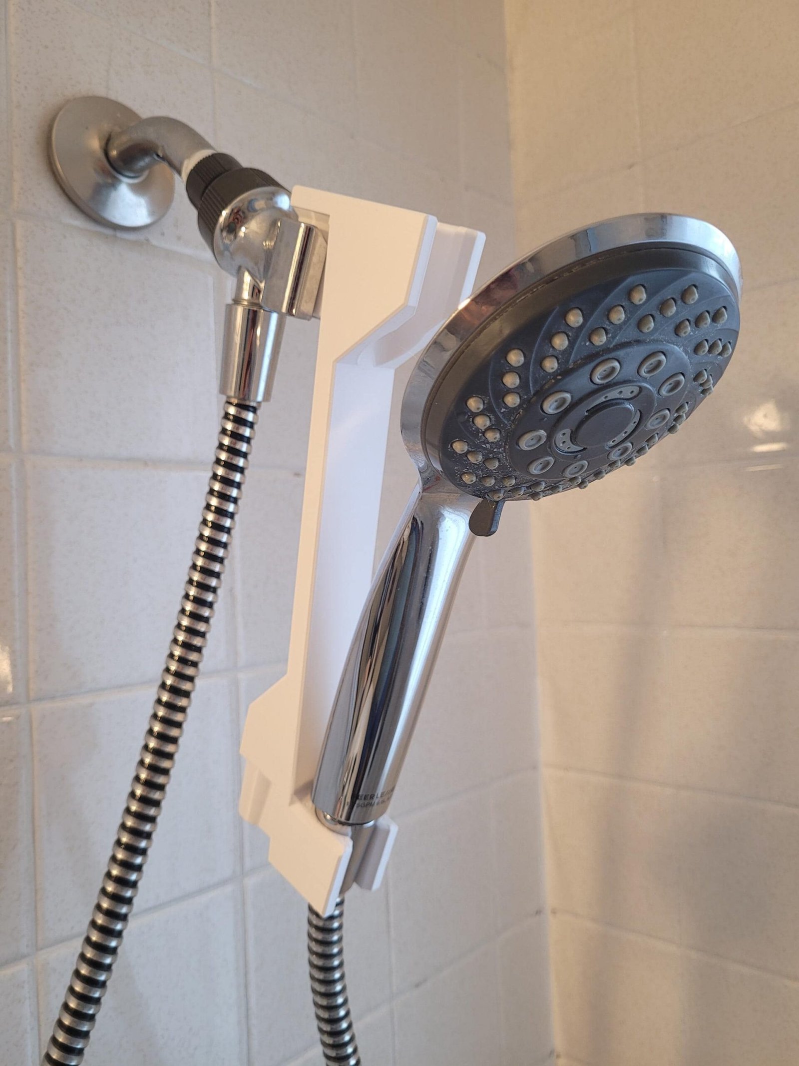 White shower head height adjuster installed on a handheld shower