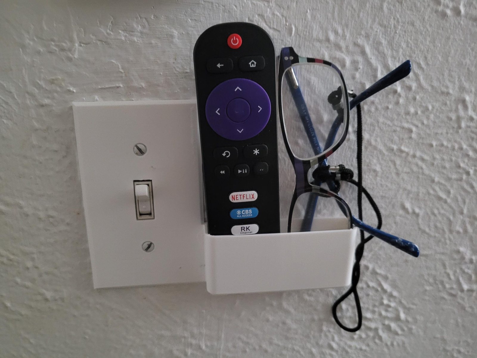 Wall switch plate phone holder installed on a light switch